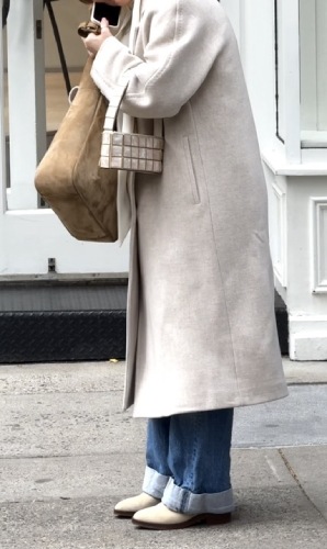 cream wool trench, a suede hobo bag, and blue cuffed jeans