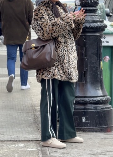forest green nylon track pants and an oversized cheetah fur coat