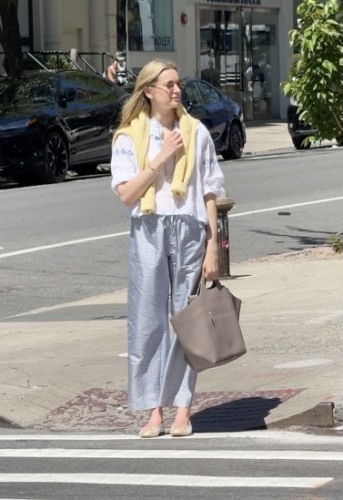 white blouse, layered with a soft yellow knit draped over her shoulders